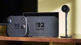 The Nintendo Switch 2 in a dock with a controller and camera on a TV stand