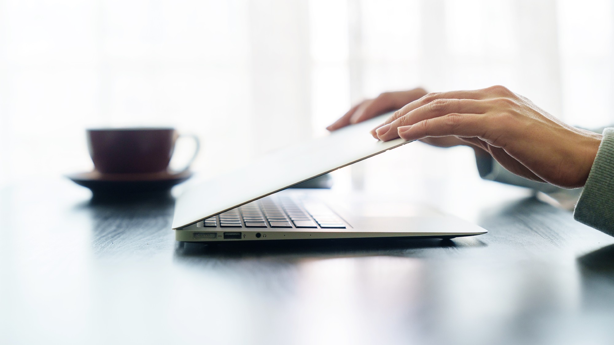 Pair of hands shutting a laptop screen closed