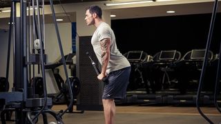 Man demonstrates the midway position of the triceps press-down