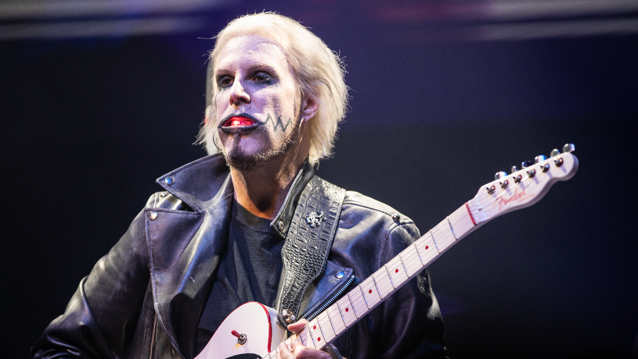 John 5 playing guitar on stage with a light in his mouth