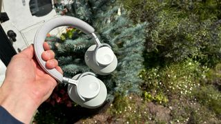 Cambridge Audio Melomania P100 over-ear headphones held in hand in garden