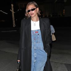 Hailey Bieber wearing black coat and overalls