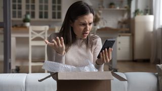 Annoyed confused customer receiving wrong parcel from internet store, checking online app, Internet service on mobile phone. Frustrated woman, client, shopper opening box, using smartphone