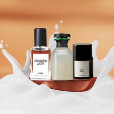 an orange backdrop with a white milk splash and three bottles of perfume in the center