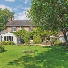 Large cottage-style garden with trees and grass, with the house in view