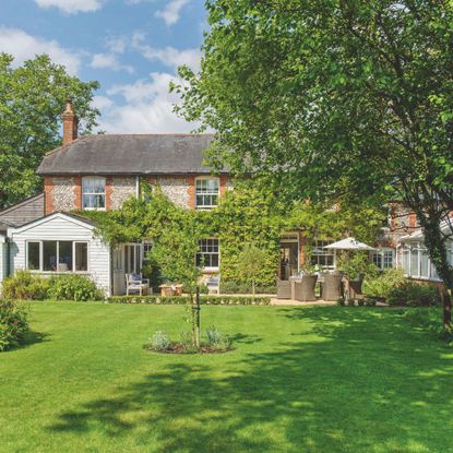Large cottage-style garden with trees and grass, with the house in view