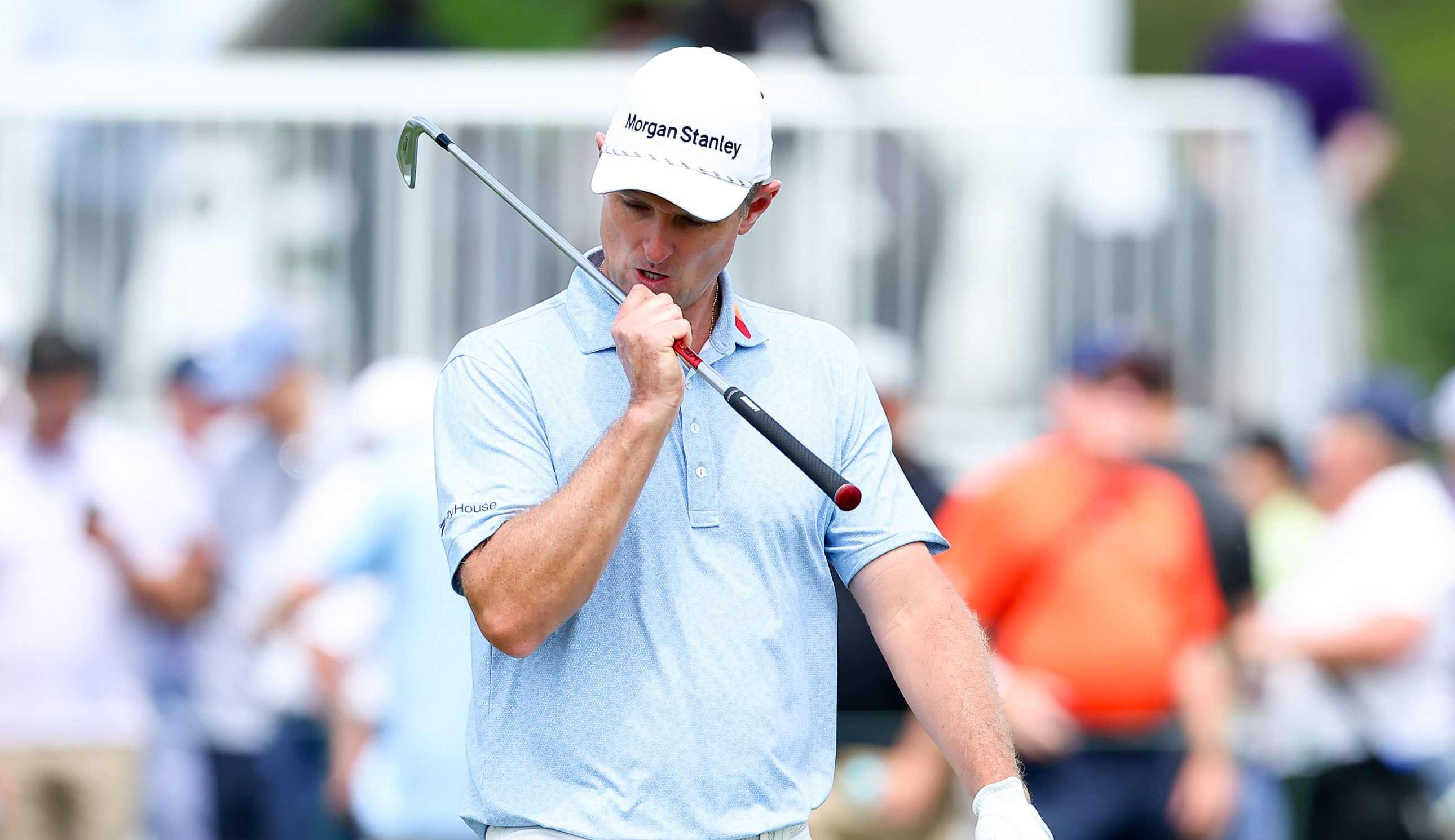 Justin Rose walks to the green holding a golf iron