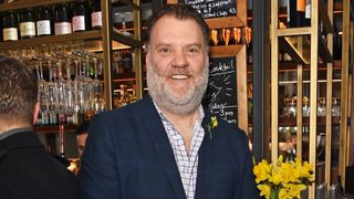 Sir Bryn Terfel wearing a suit and smiling at the camera