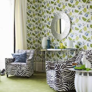room with leaf printed wall and round mirror on wall