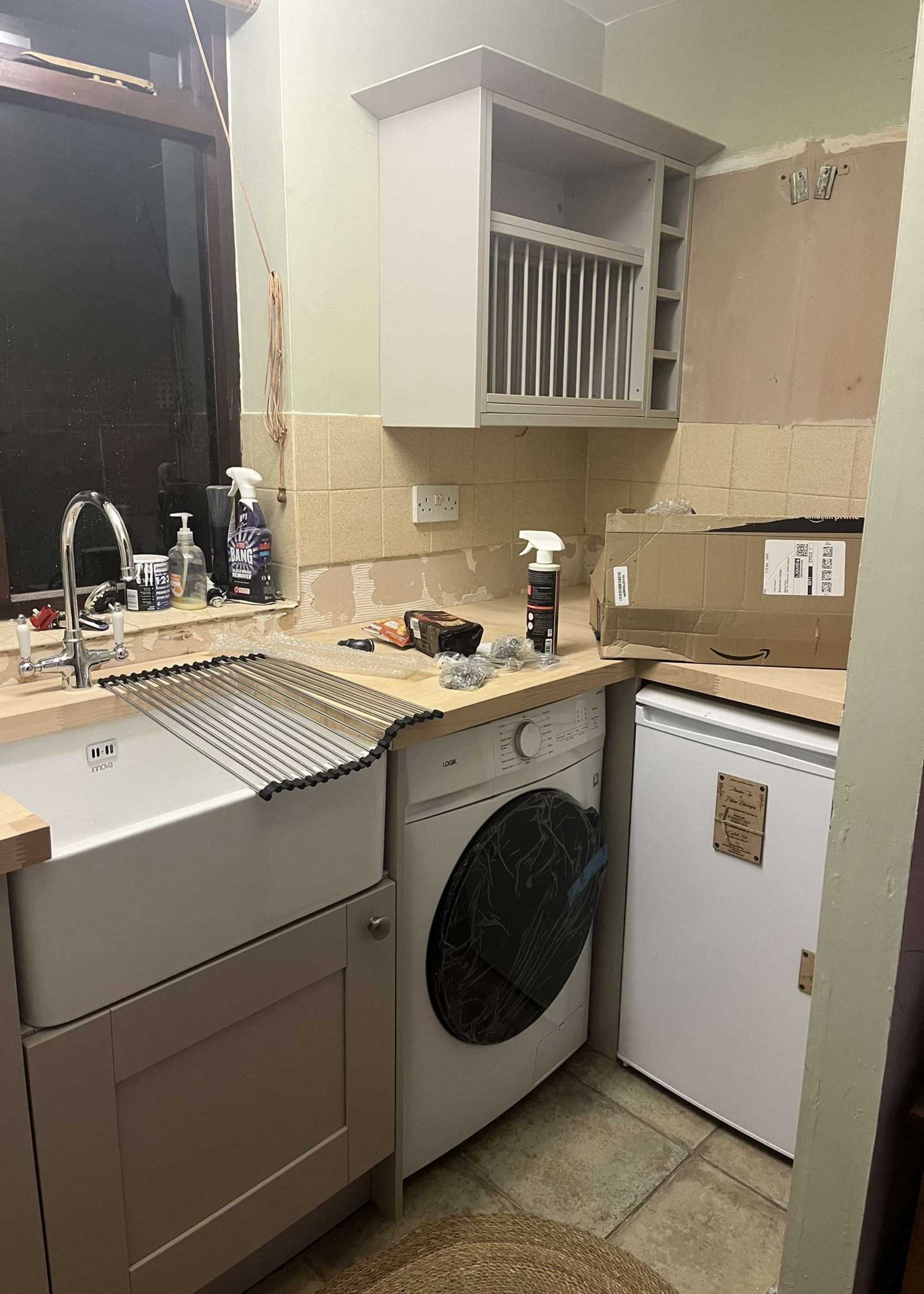 A kitchen during a renovation with dated tiles and exposed plasterboard