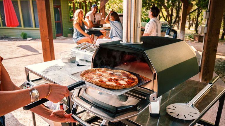 What can you cook in a pizza oven? An Ooni pizza oven with people in the background