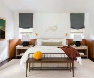 neutral bedroom with a symmetrical design that features two bedside windows with matching blinds, two matching nightstands and matching table lamps