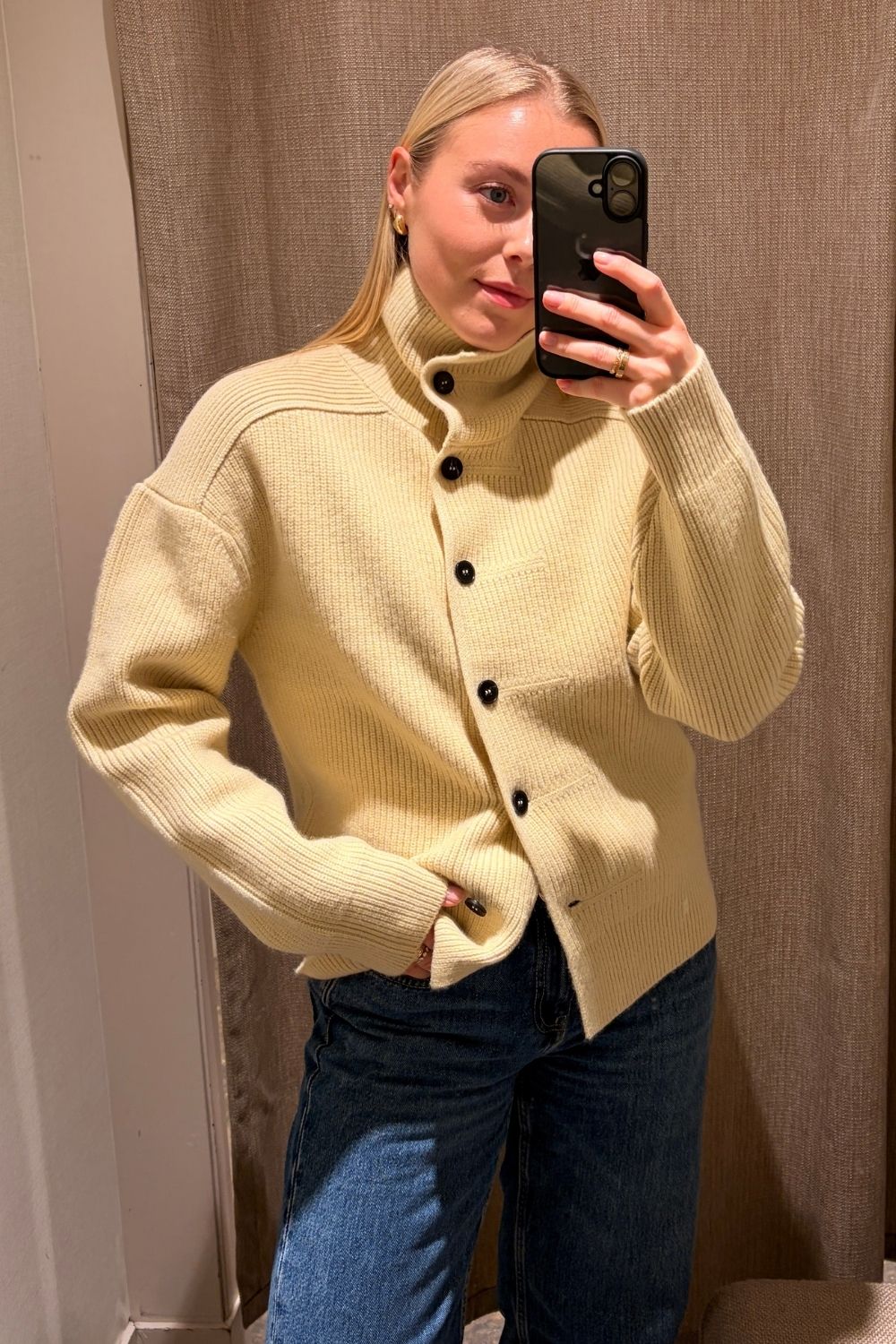 Woman wears yellow funnel-neck cardigan and blue jeans