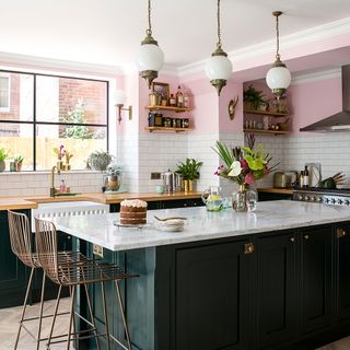 kitchen with pink and white tile wall dark green cabins white counter and lamps