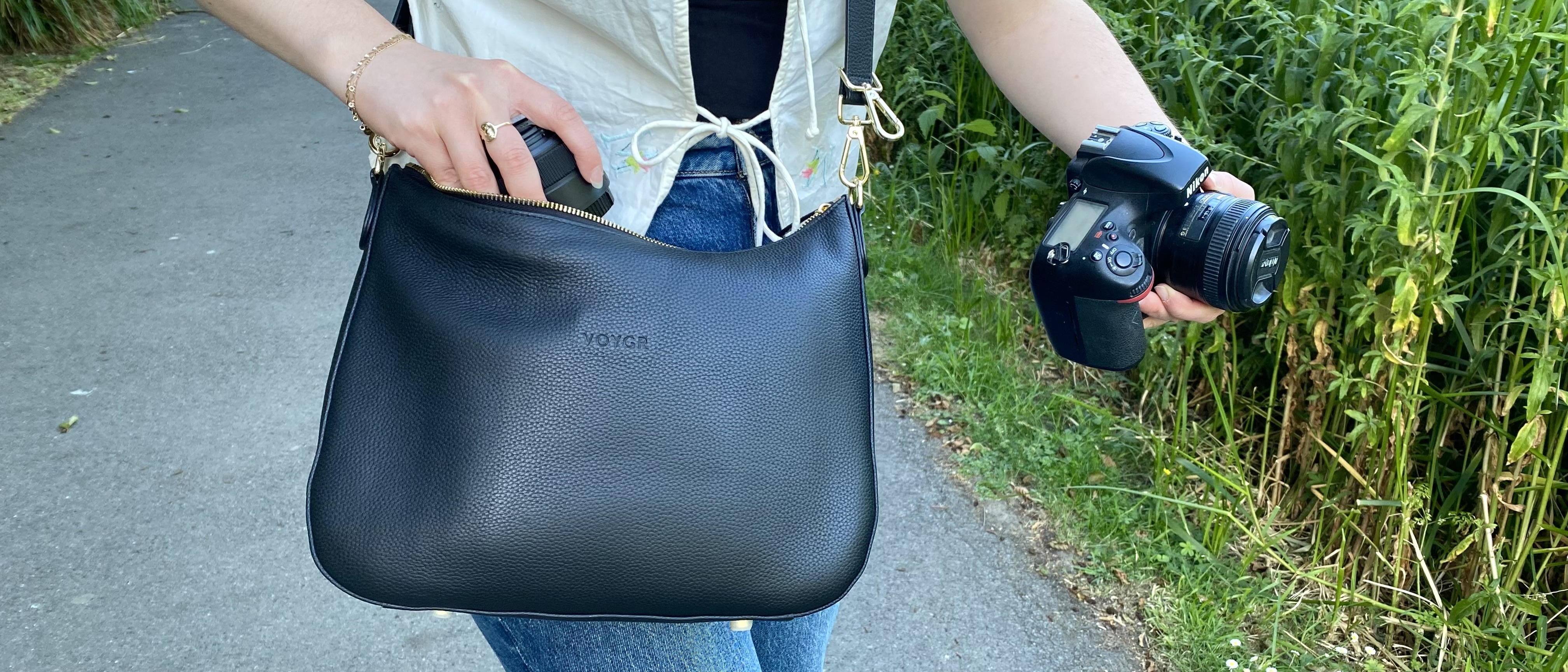 Person wearing a Voygr 1 camera bag and removing lens