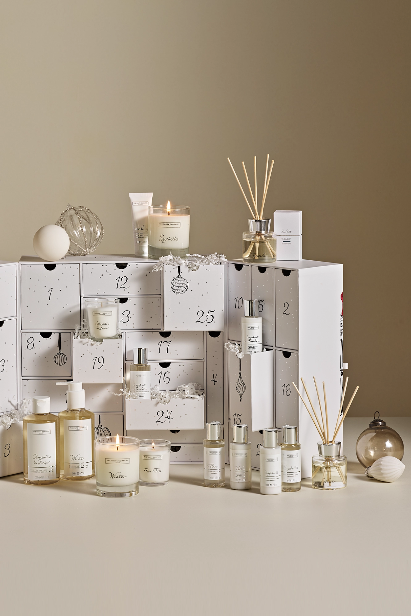 A white advent calendar with home fragrance items like reed diffusers, glass candles, essential oils, and more