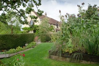 exuberantly-planted vegetable garden, in which globe artichokes and oat grass Stipa gigantea rise above raised beds