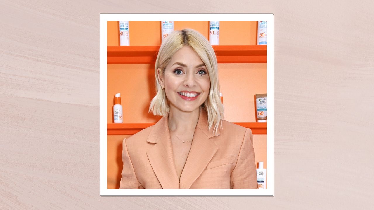 Image of Holly Willoughby smiling with a curled blonde bob and wearing a peach blazer, on a pink background