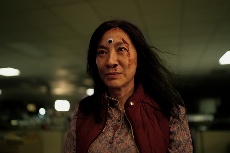 Michelle Yeoh with googly eye in the middle of her forehead and blood over her left eye
