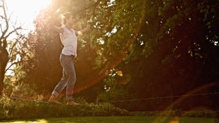 Young woman slacklining in park on sunny day, North Rhine-Westphalia, Germany