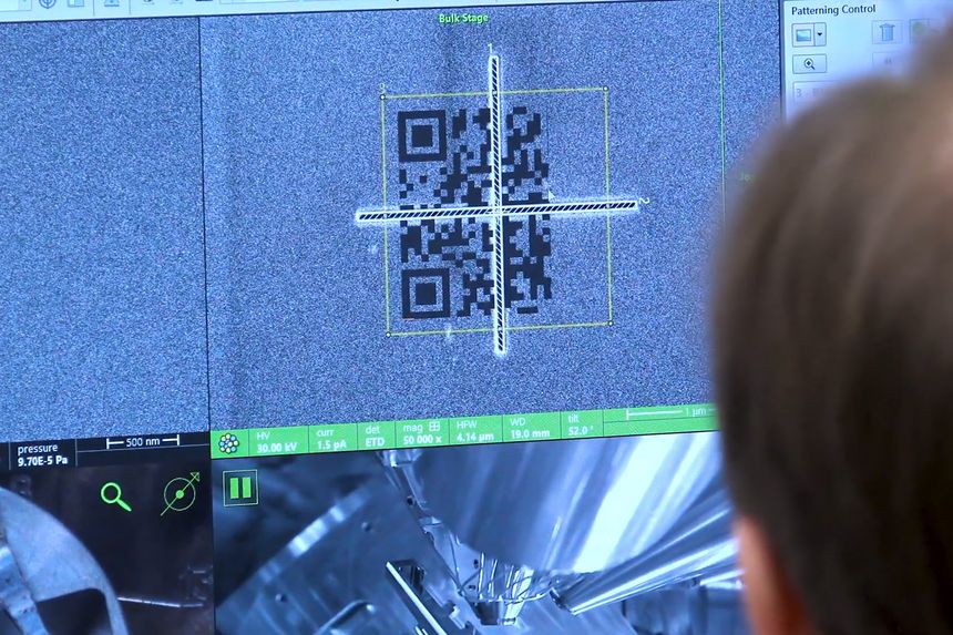 A close up of a computer monitor showing a grayscale image of a QR code being printed onto a ceramic surface.