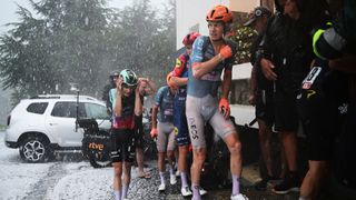 Matthew Riccitello and Jack Haig run for shelter from hail during La Vuelta a Espana 2026