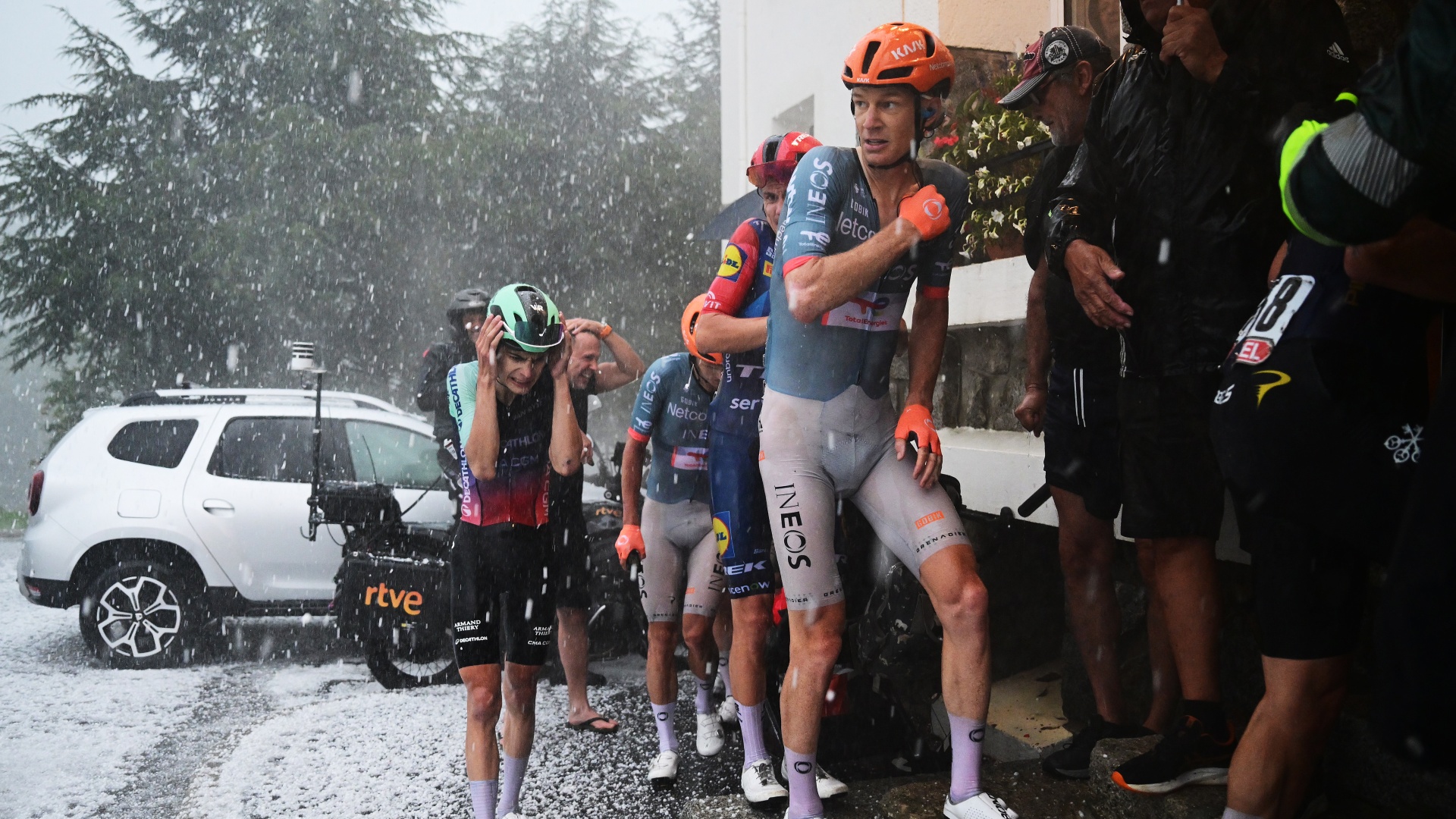Matthew Riccitello and Jack Haig run for shelter from hail during La Vuelta a Espana 2026