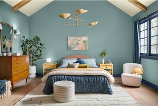 A bedroom with a vaulted ceiling with wooden beams and blue walls