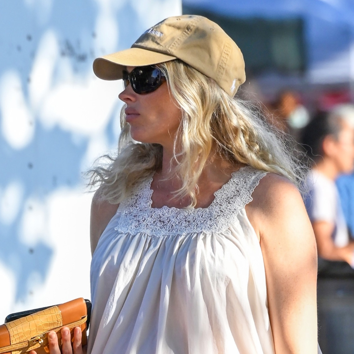Elsa Hosk wearing a white sleep dress and flip-flops with a tan baseball cap
