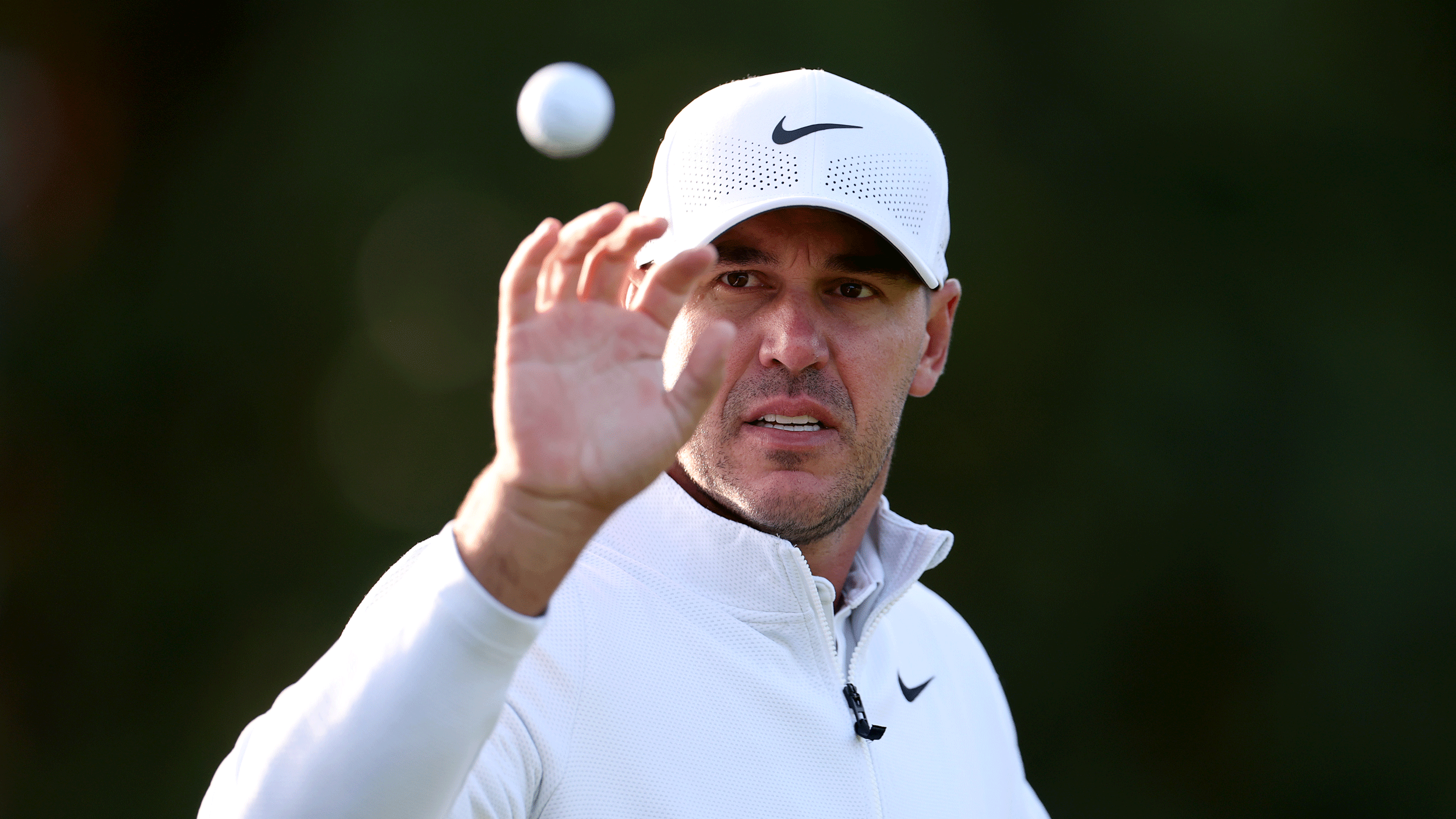 Brooks Koepka prepares to catch a golf ball in his right hand during the 2025 BMW PGA Championship