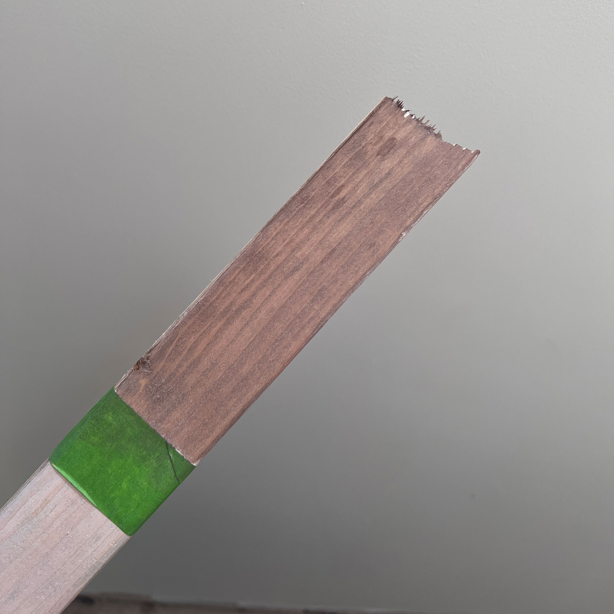 Stick of wood with half stained a darker colour