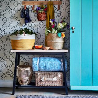 wicker baskets, flowers and blanket on entrance hallway with vibrant blue door