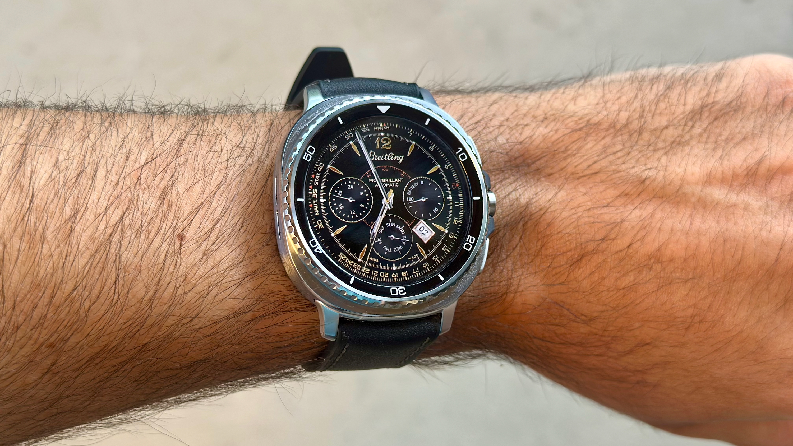 The Samsung Galaxy Watch 8 Classic on a person's wrist, showing a custom watch face from the TIMEFLIK app of a classic Brietling watch.