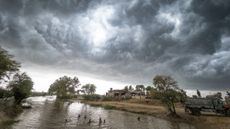 Monsoon storm clouds gathering above a river in southern Pakistan. Children are playing and swimming in the river.