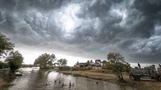 Monsoon storm clouds gathering over a river in southern Pakistan. Children are playing and swimming in the river.