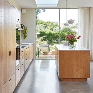 A contemporary, Scandi-style kitchen with pale wooden kitchen cabinets and kitchen island