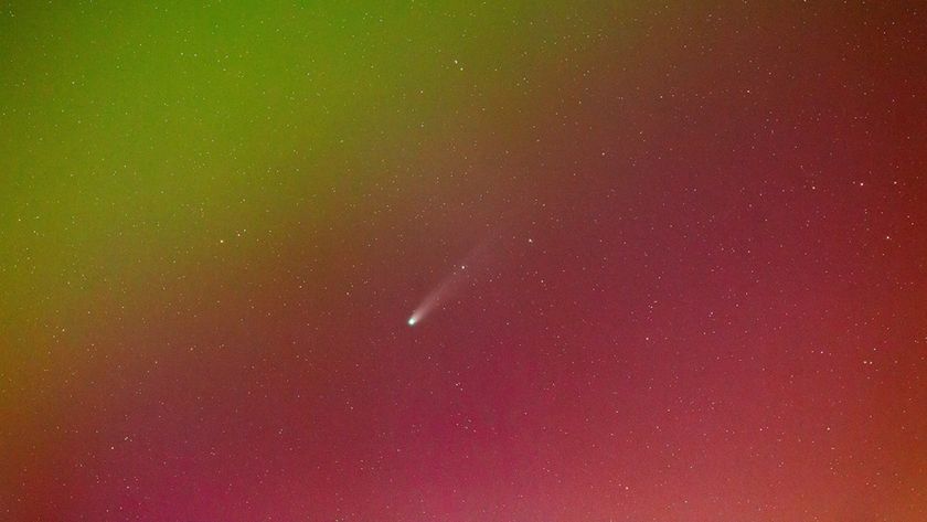 A close-up photo of Comet Lemmon appearing to fly through red and green auroras