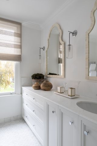 white bathroom with marble floor, white cabinets, double mirrors, blind