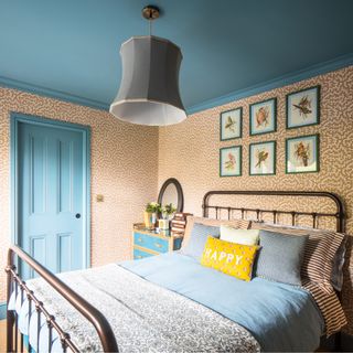 A bedroom with a micro-print wallpaper and a sky blue-painted ceiling and cornicing matching the door