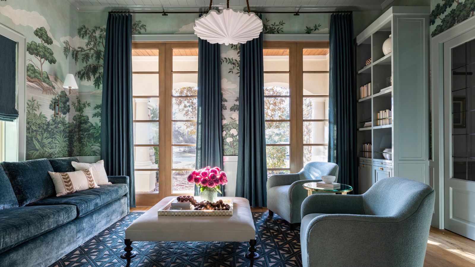 traditional living room with light teal wall mural, teal sofa and armchairs, blue rug and curtains