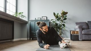 Man laying on workout mat with dog