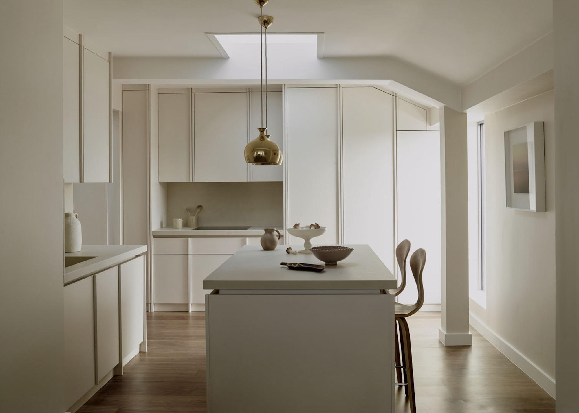 A minimalist kitchen with an island and bar stools next to the island. There are also two pendant lights hanging above the island.