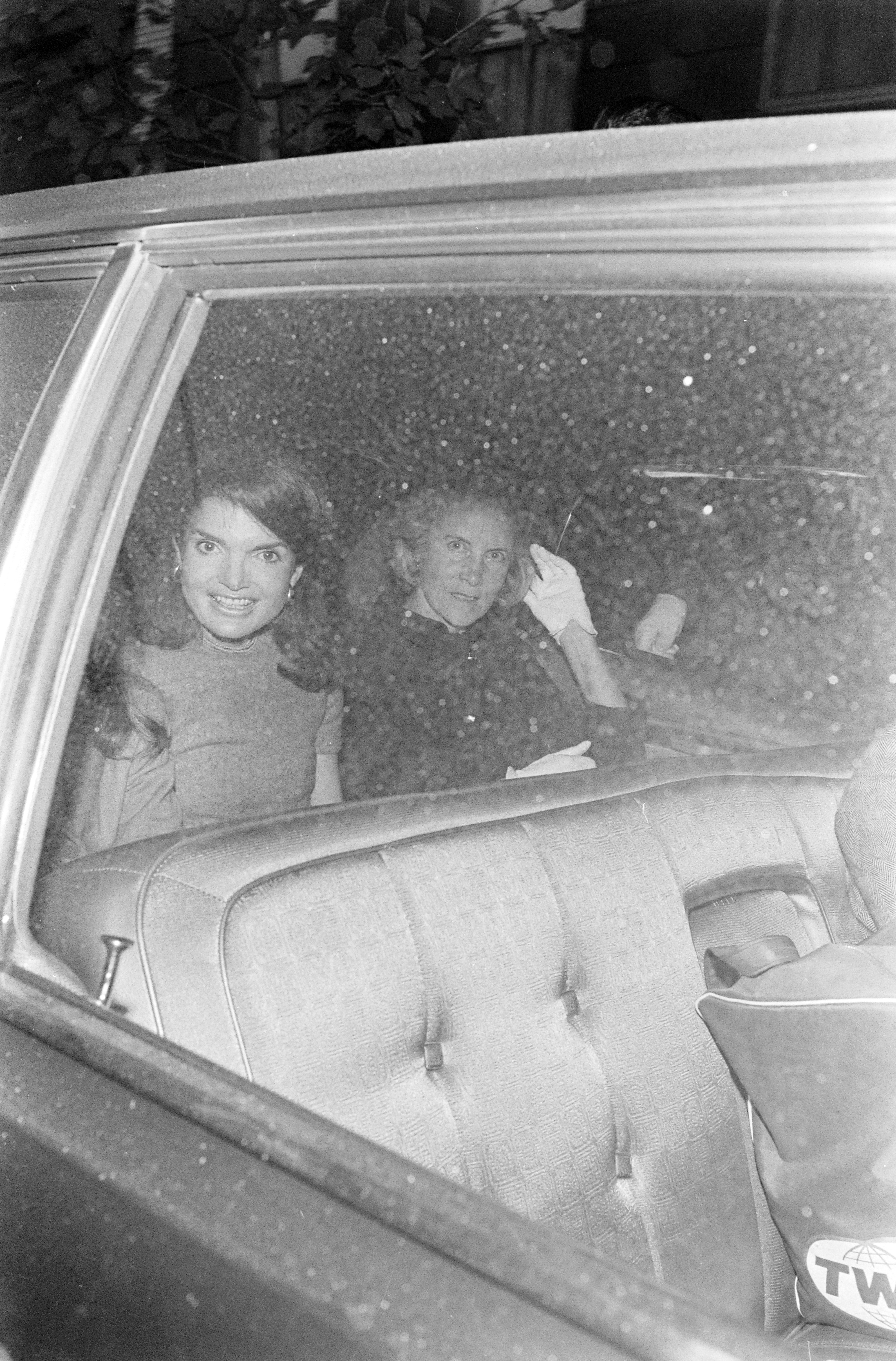 Jacqueline Kennedy leaving her apartment for her wedding to Aristotle Onassis. She&#039;s sitting in the back of a car next to Bunny Mellon