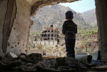 A boy stands in the rubble of a home in Yemen.