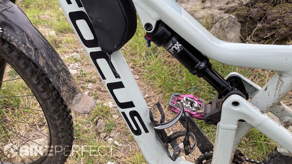 Focus Jam 6.9 trail bike leaning against a rock next to a singletrack trail