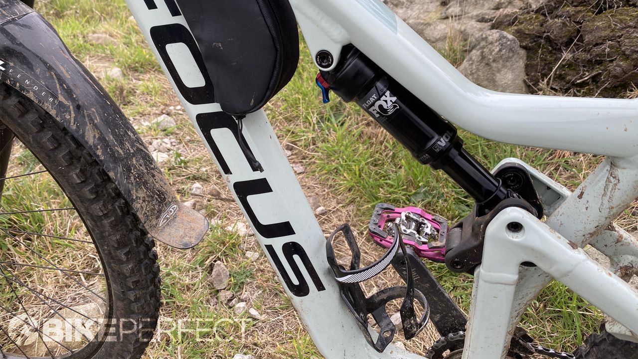Focus Jam 6.9 trail bike leaning against a rock next to a singletrack trail