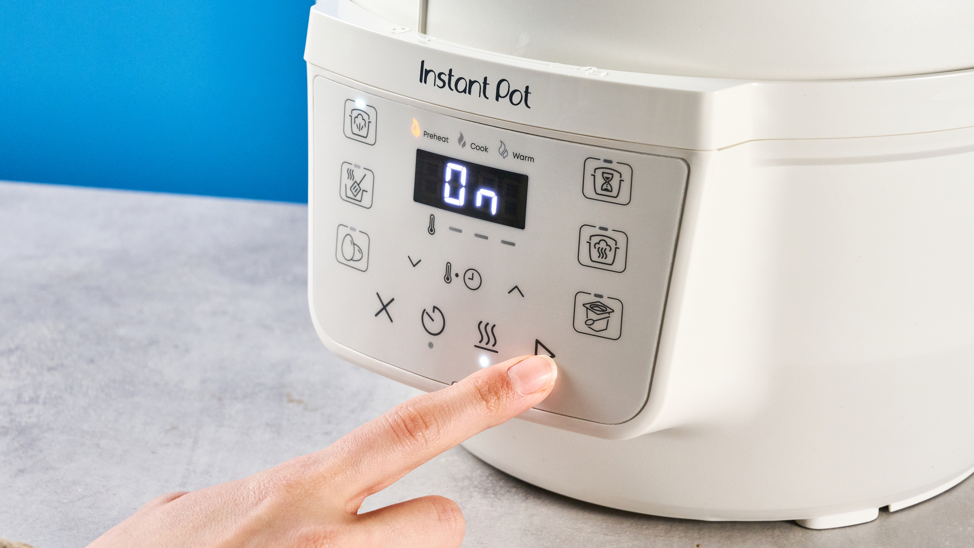 the instant pot rio mini / instant pot mini in white photographed against the blue tom's guide background showing its inner pot, accessories, and cooking programs