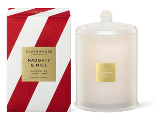 Soy candle in wax jar next to white and red striped box