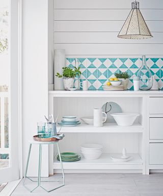 A white kitchen with open shelves and blue and white tiles.