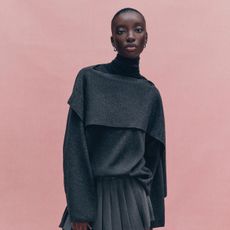Woman wears draped grey top, grey pleated skirt